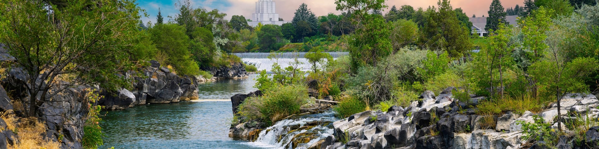 A river flowing through a rocky landscape with trees and a distant tower.