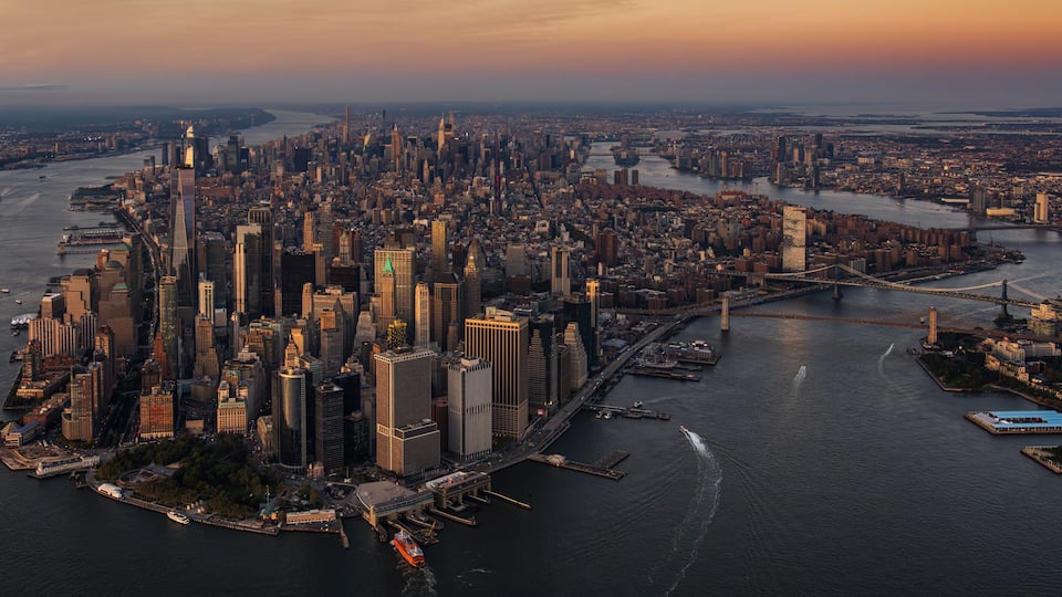 A cityscape with a dense cluster of high-rise buildings, a river, and a bridge.