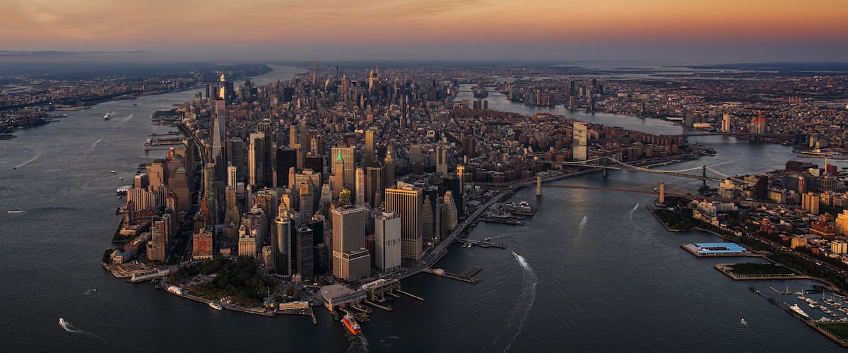 A cityscape with a dense cluster of high-rise buildings, a river, and a bridge.