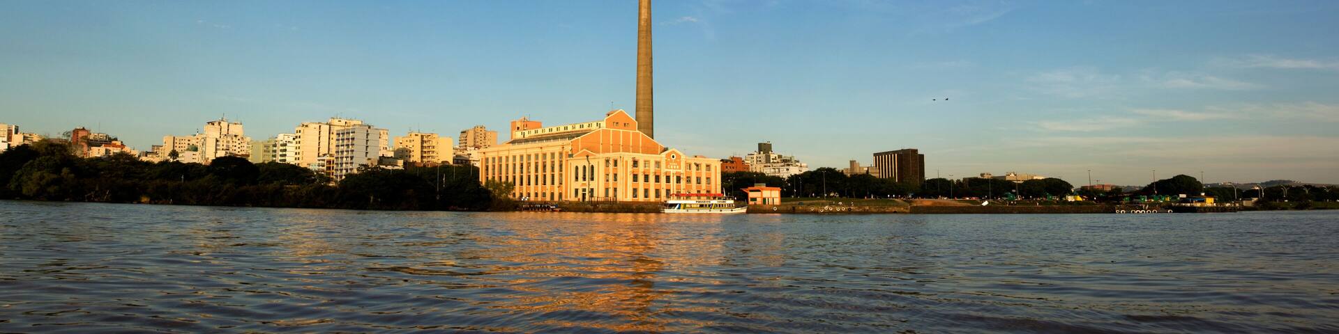 A river with a tall smokestack and a building with a pointed roof.