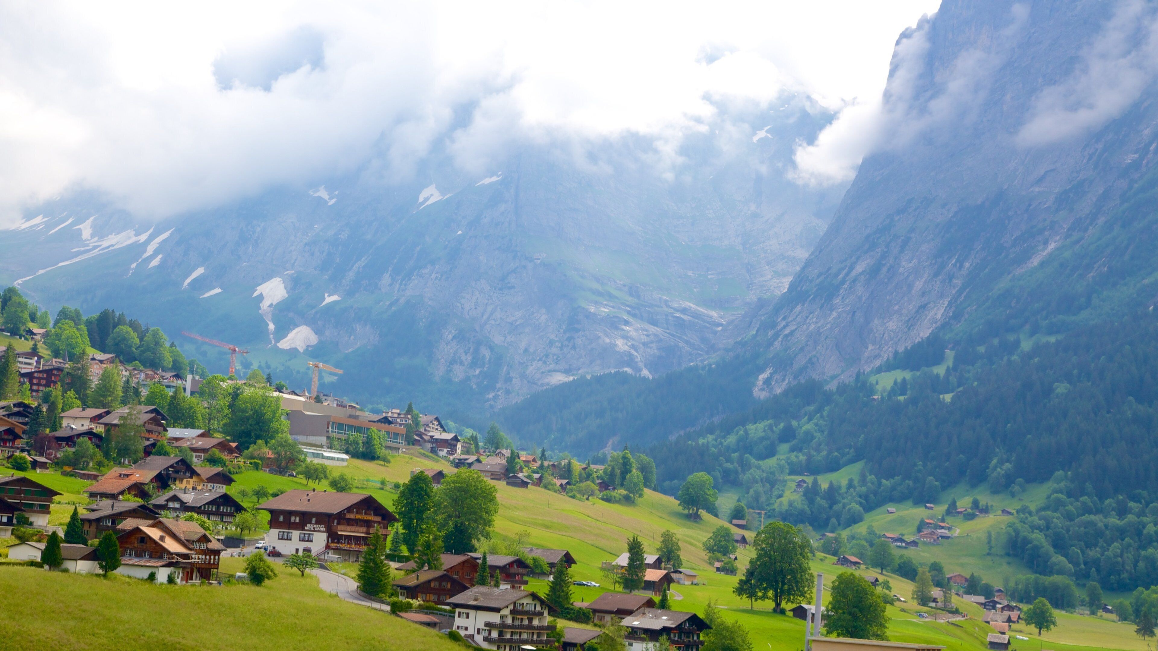 A mountain village with houses, trees, and a valley.