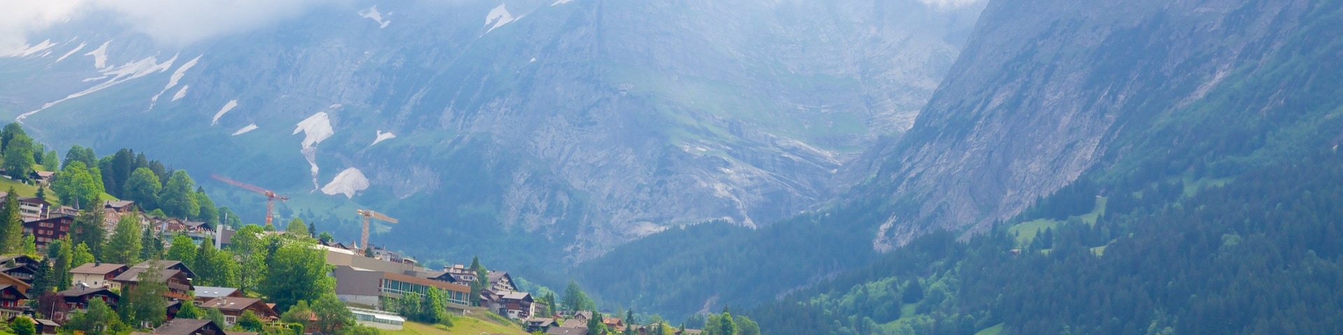 A mountain village with houses, trees, and a valley.