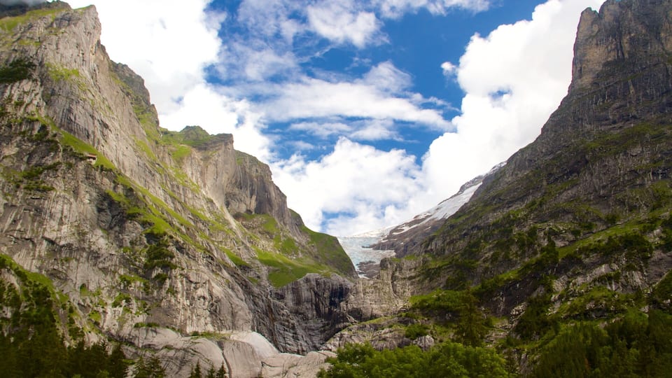 A mountainous landscape with a glacier and a small cabin.