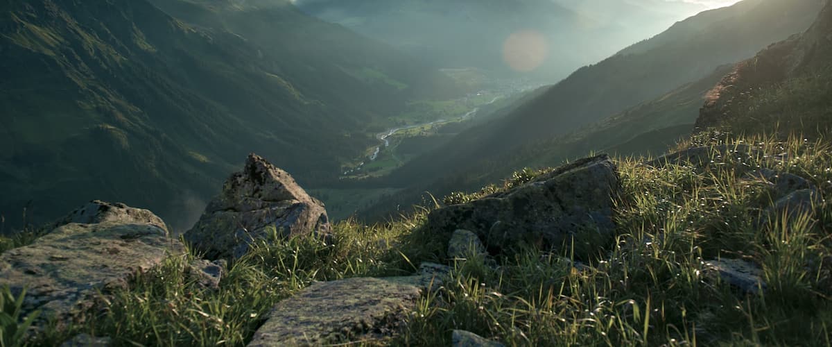 A mountainous landscape with a valley, rocky outcrops, and a river.