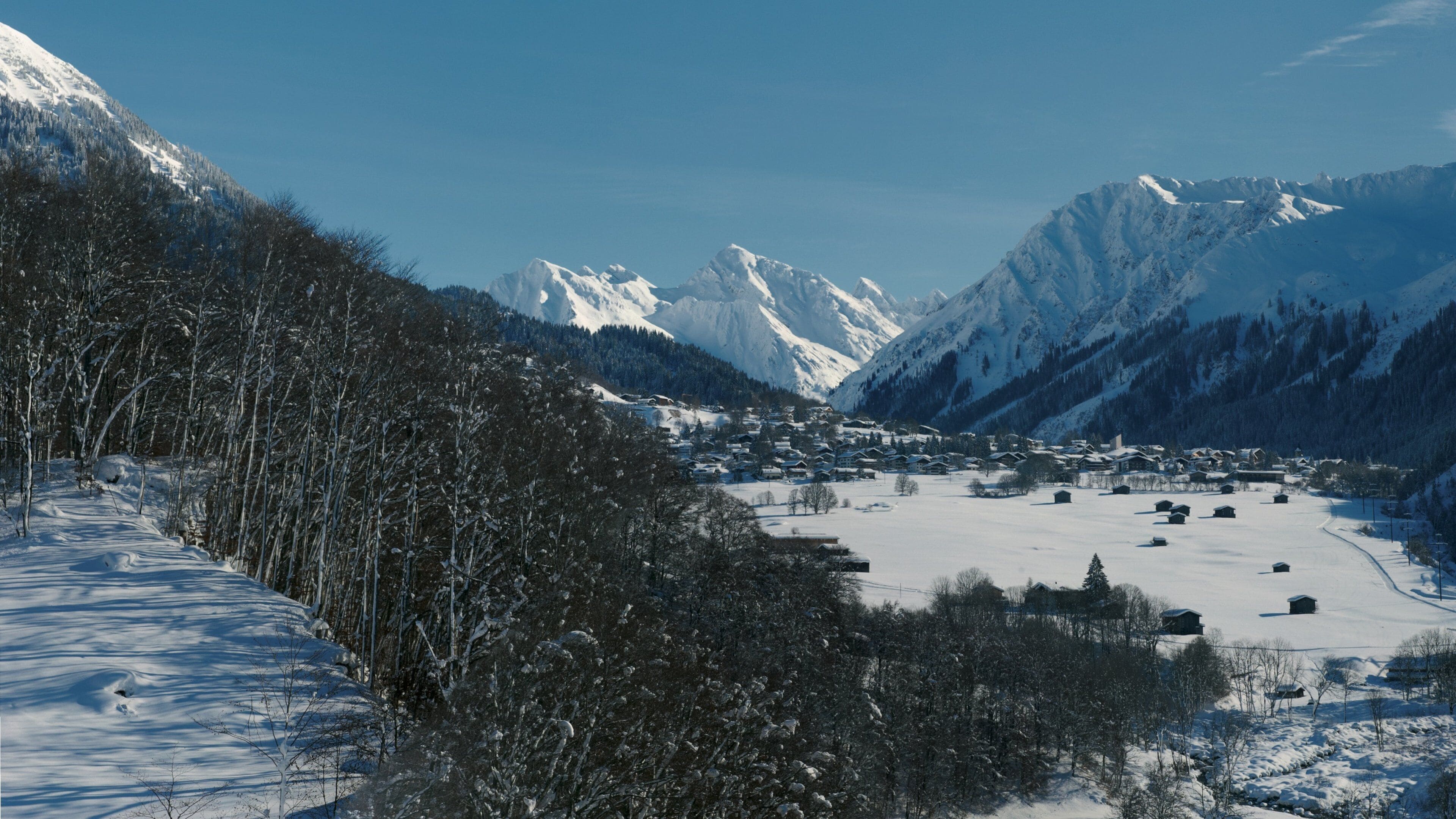 A snow-covered mountain landscape with a village nestled in the valley.