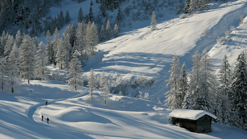A snow-covered mountain with a wooden cabin and skiers.