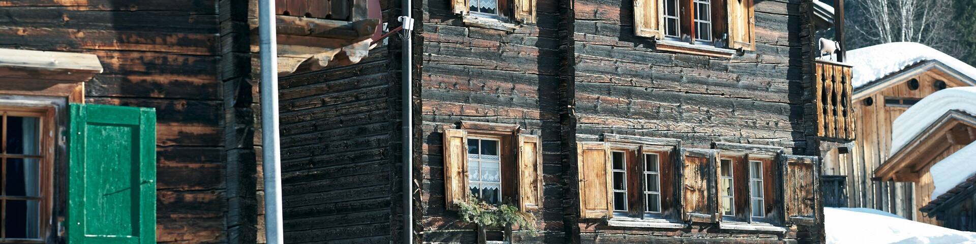 A rustic wooden house with multiple windows and a deer head mounted on the wall.