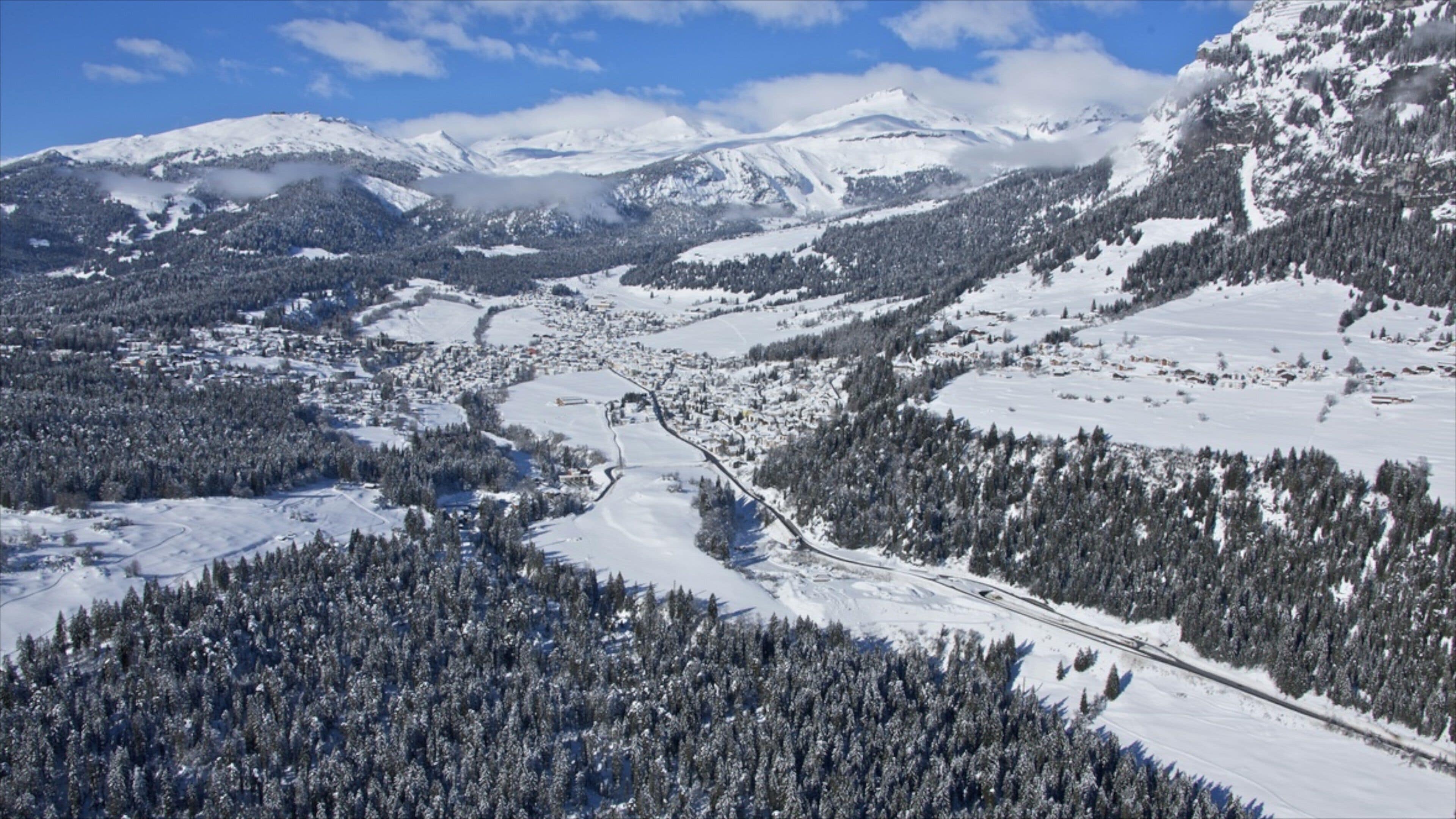 A snow-covered mountainous landscape with a town nestled in the valley.