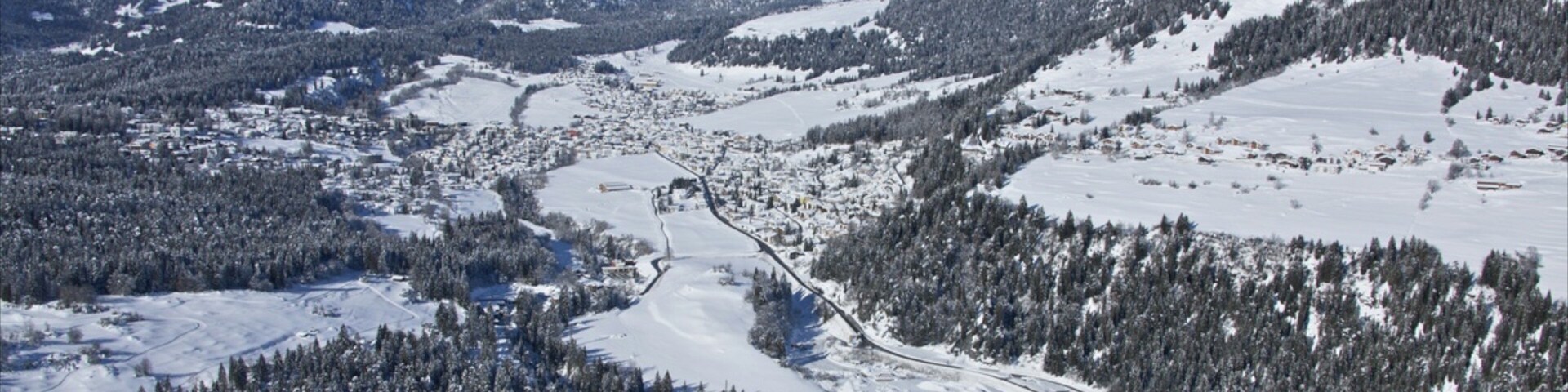 Paisagem montanhosa coberta de neve, com uma cidade aninhada no vale.