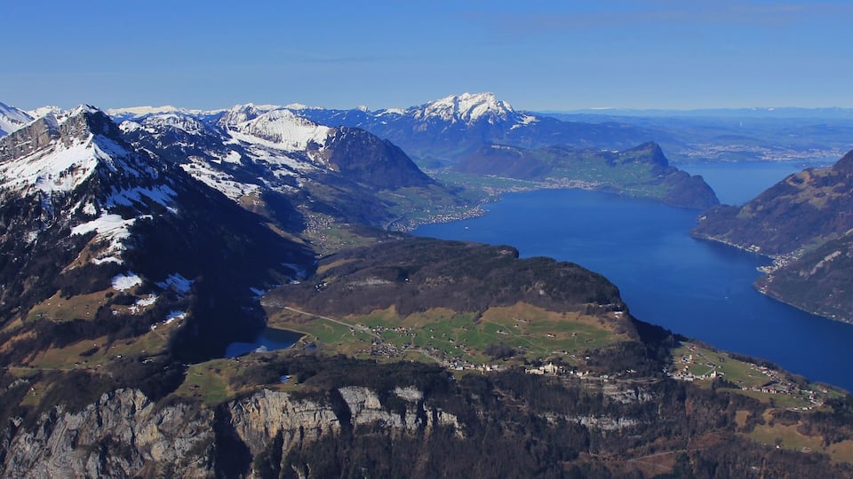 A mountainous landscape with a lake and snow-capped peaks.