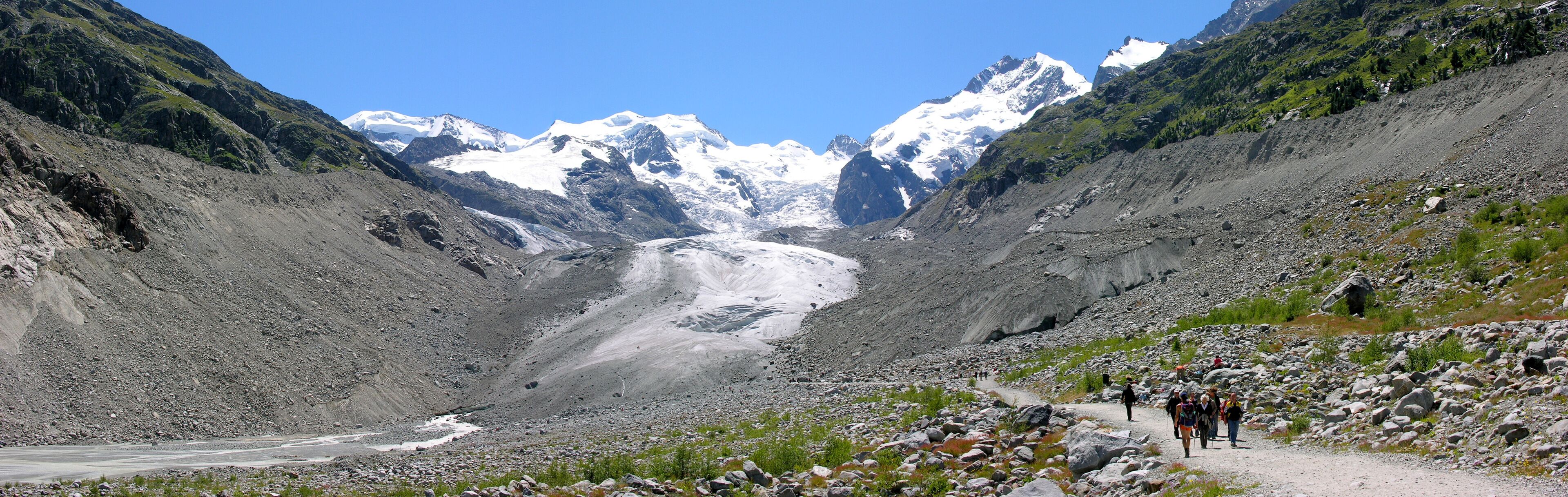 A glacier valley with a rocky path and hikers.