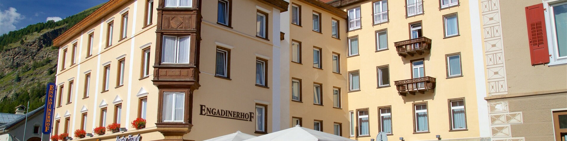 Una calle con un edificio que dice "Engadinhof" y un carrito de comida al aire libre.