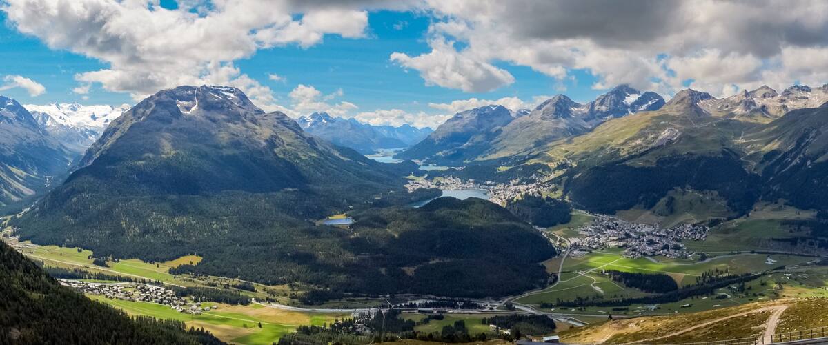 A mountainous landscape with a valley, a lake, and a small town.