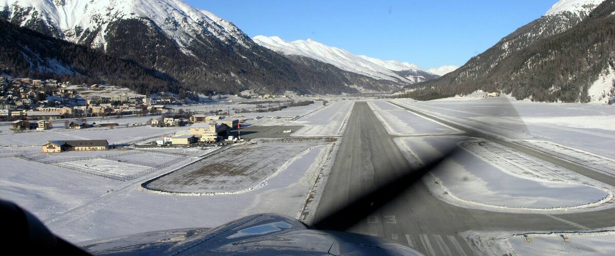 A snow-covered runway with mountains in the background.