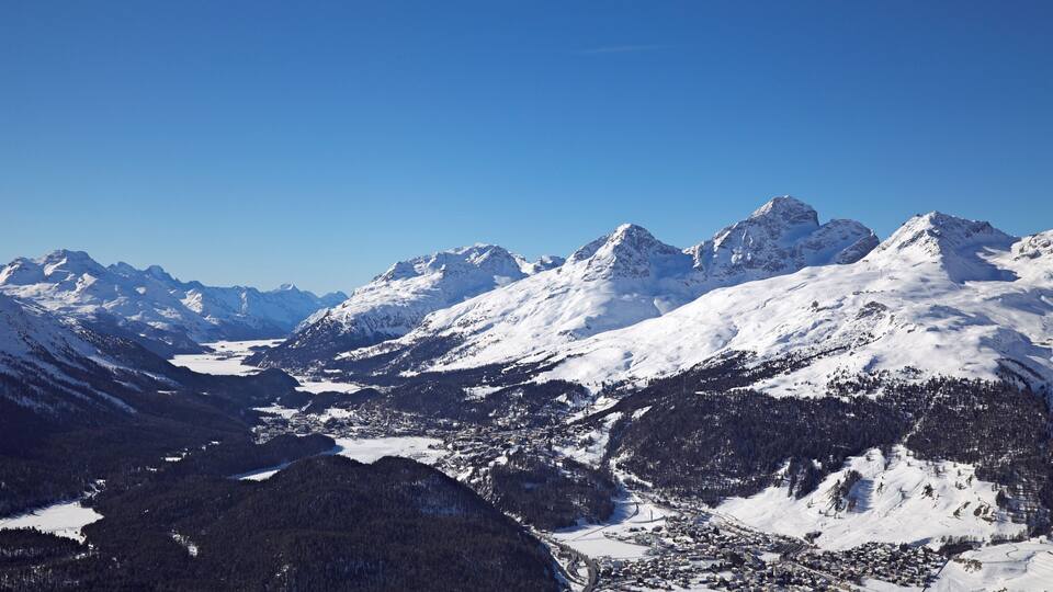A snow-covered mountain range with a town nestled in the valley.