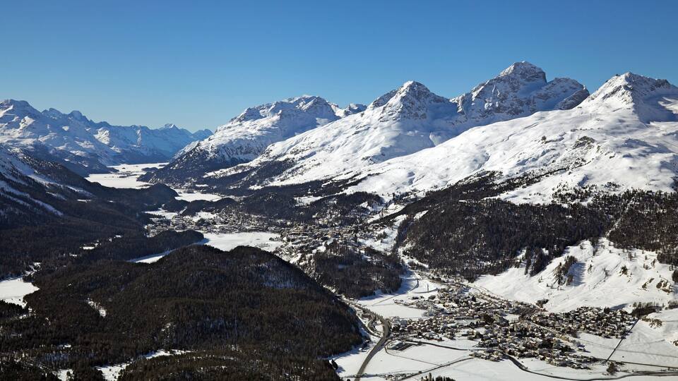 A snow-covered mountain range with a town nestled in the valley.