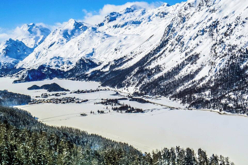 Une chaîne de montagnes enneigées, avec une vallée et un lac.