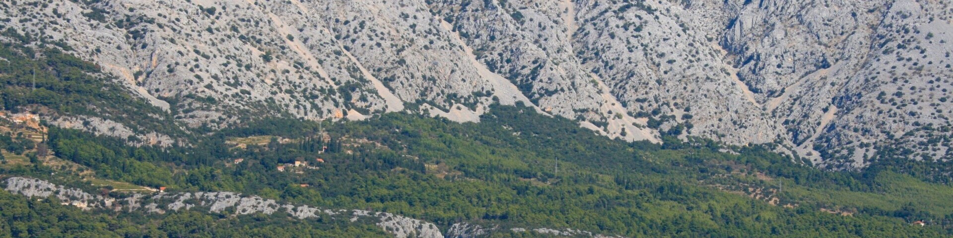 Un pueblo costero con edificios y una cordillera al fondo.