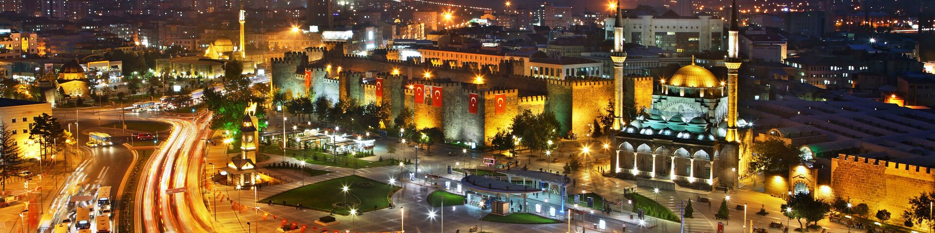 Un paisaje urbano nocturno con edificios iluminados, una glorieta y una estructura cúpula destacada.