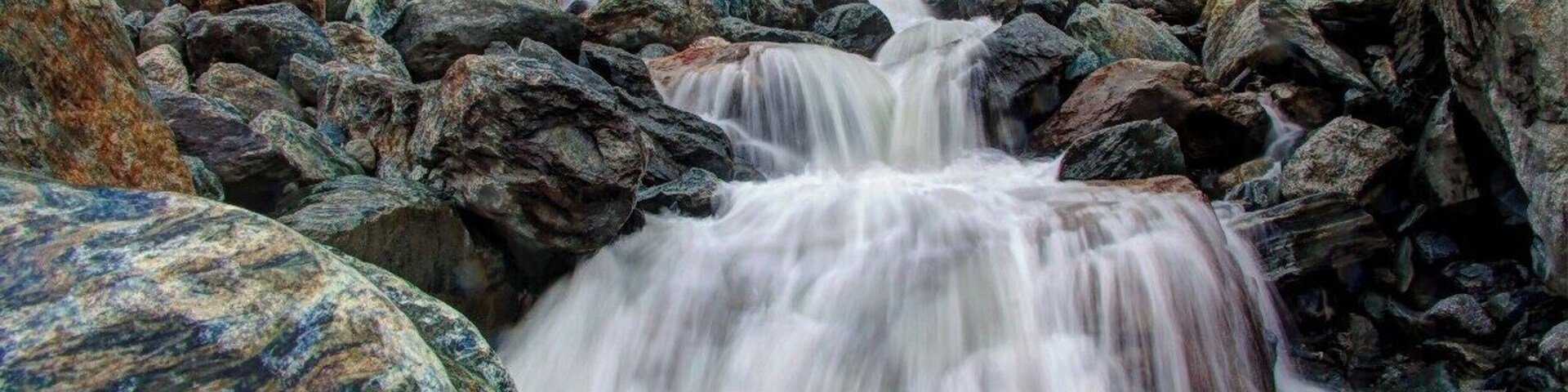 Uma cascata em queda, cercada por grandes pedras.