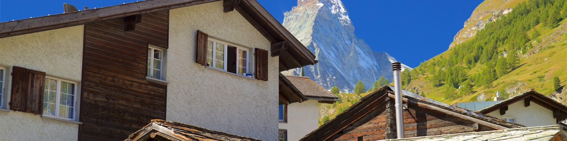 Un village de montagne aux maisons traditionnelles en bois, avec un sommet montagneux imposant en arrière-plan.