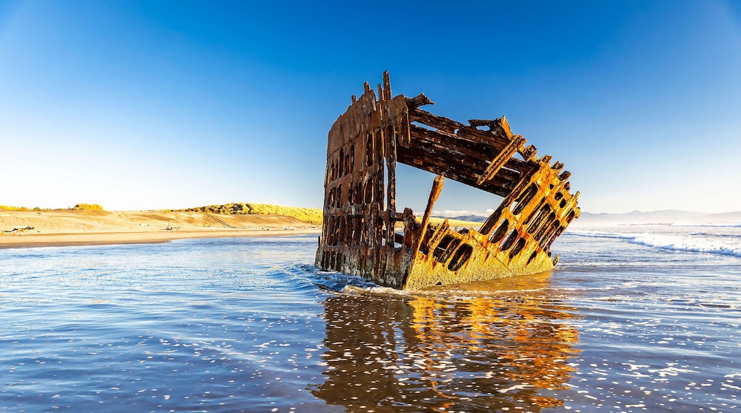 A rusted shipwreck in the ocean with clear skies.