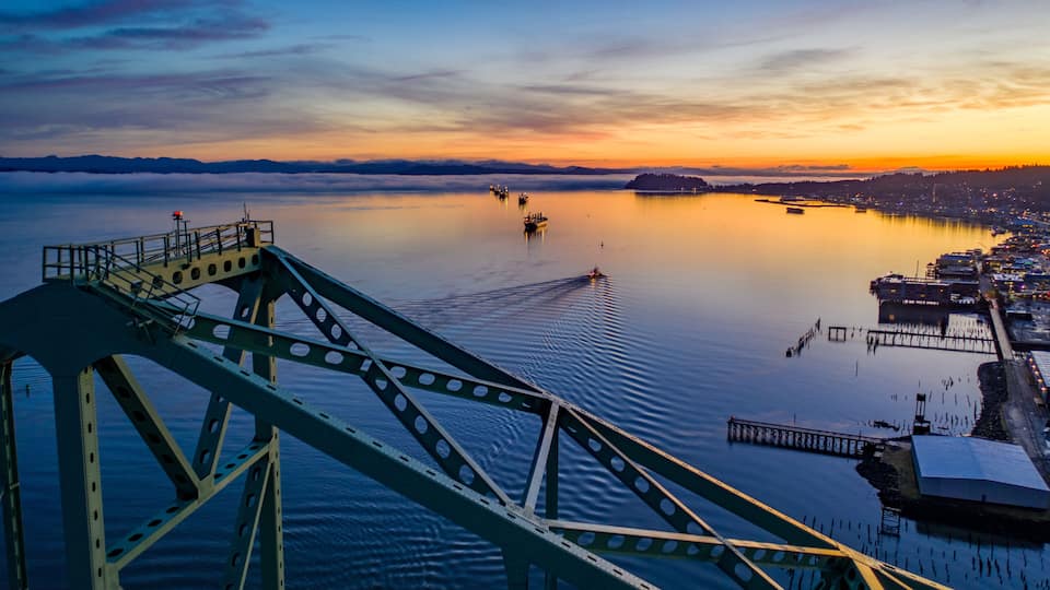 A bridge over calm water with a sunset in the background.