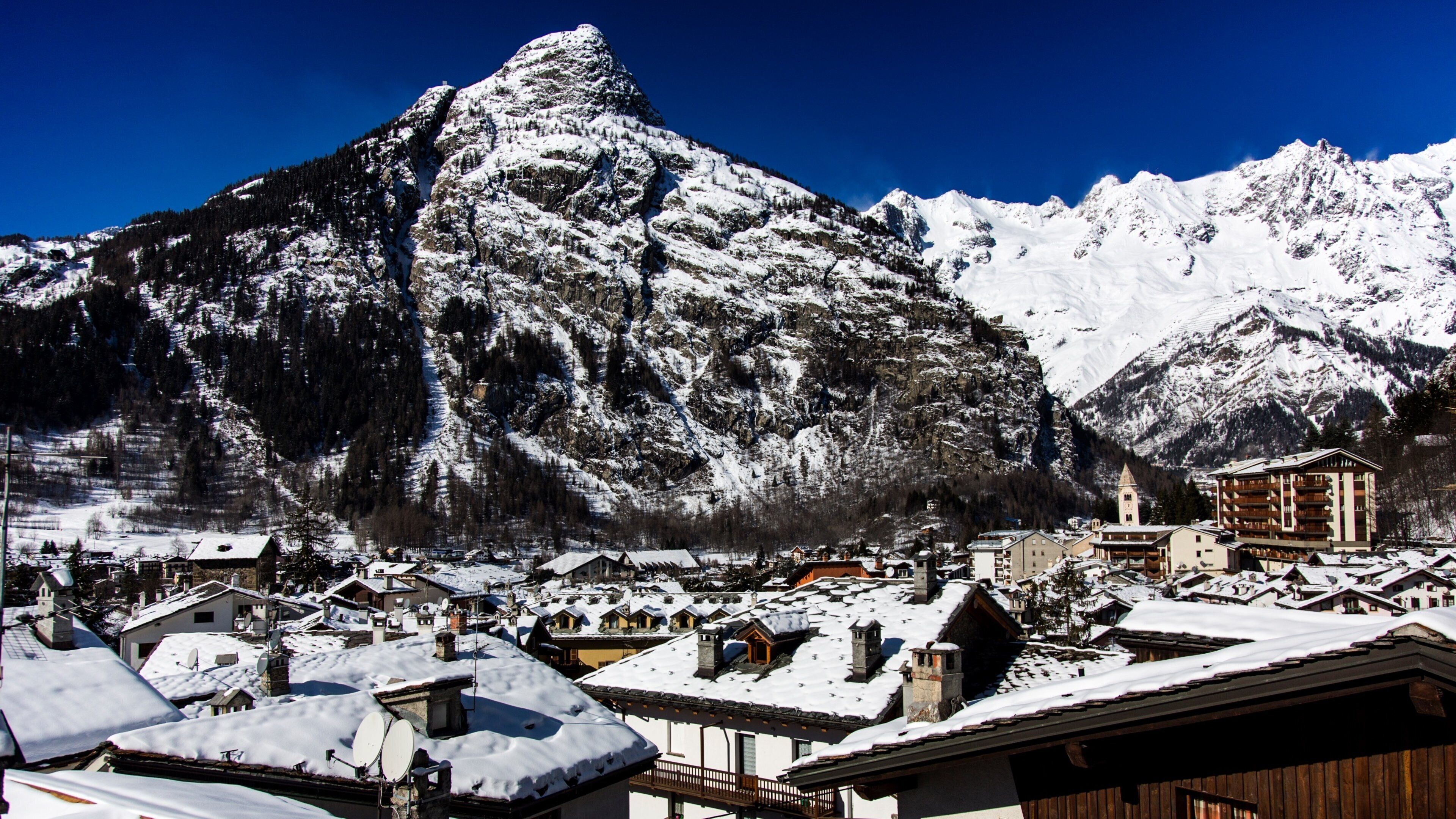 A snow-covered mountain town with buildings and a prominent peak.
