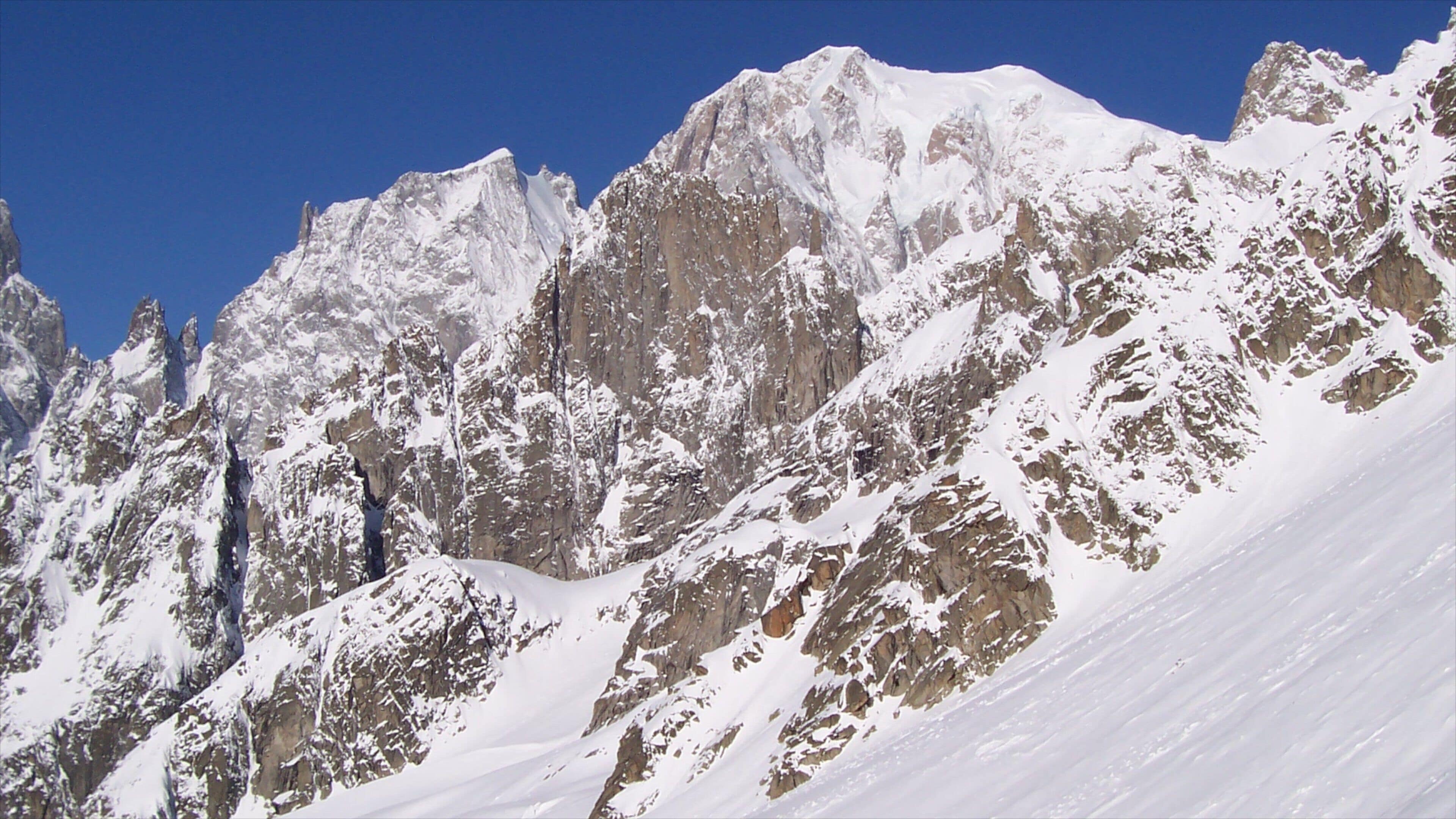 A snow-covered mountain range with sharp peaks and rugged terrain.