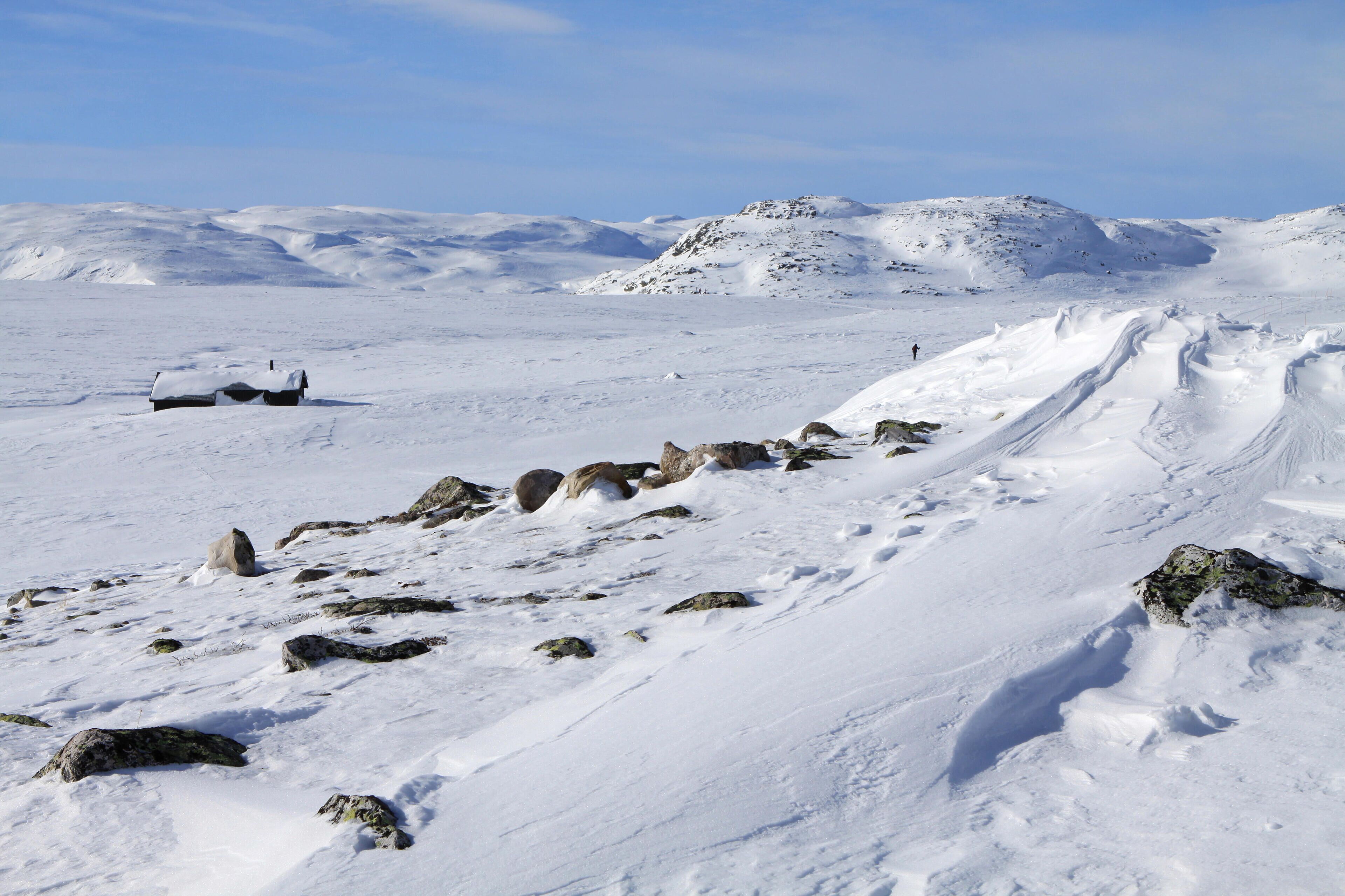 A snowy mountain landscape with rocky outcrops and a clear sky.