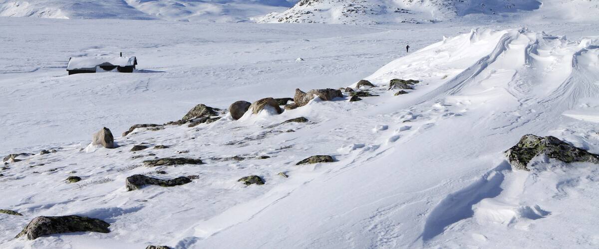 A snowy mountain landscape with rocky outcrops and a clear sky.