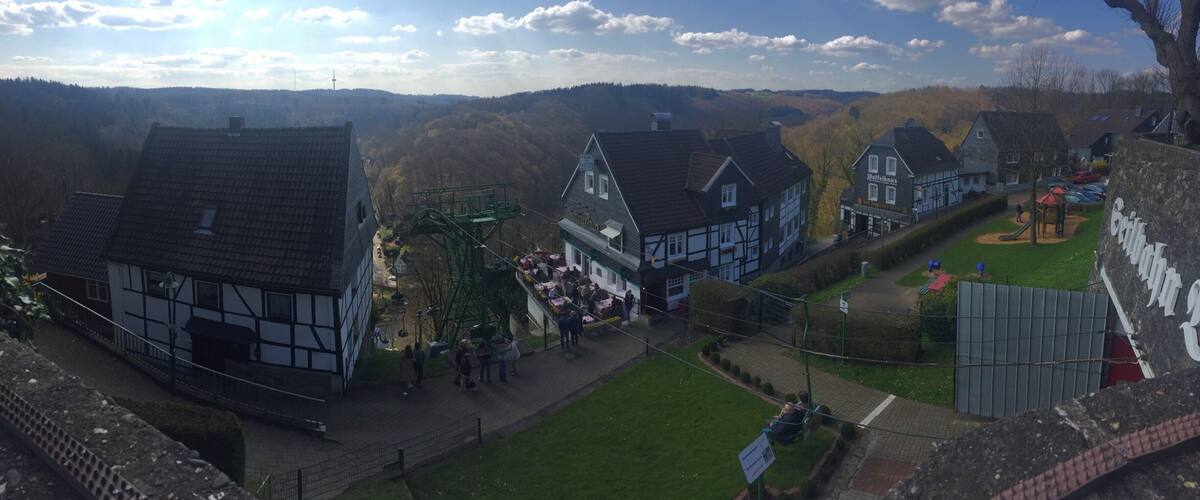 A village with traditional half-timbered houses, a playground, and a church steeple in the background.