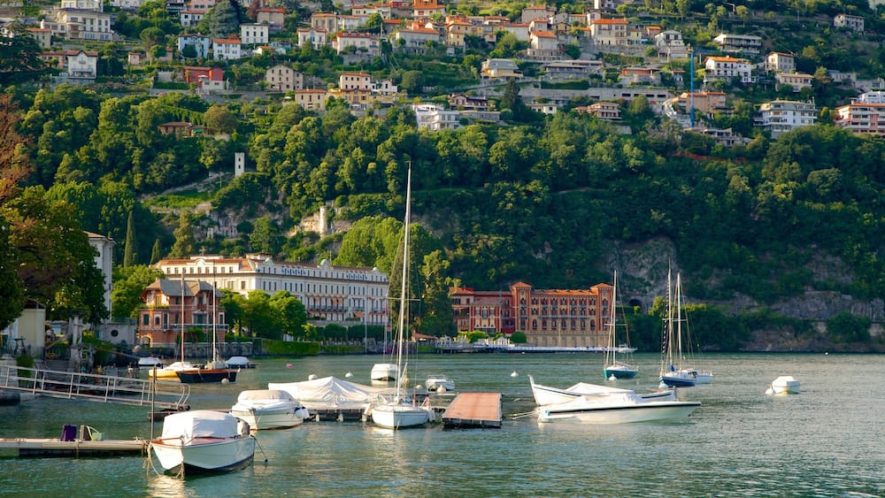 Un port où des bateaux sont amarrés, entouré d’une colline parsemée de bâtiments et de verdure.