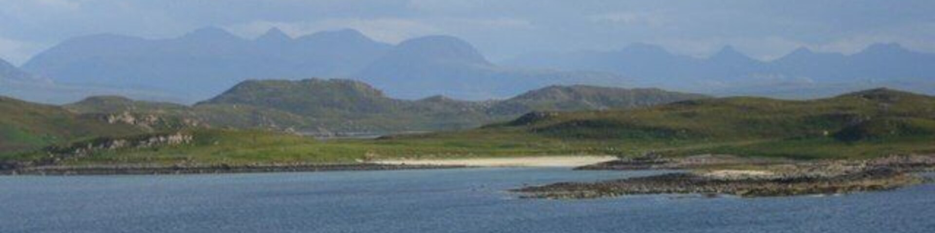 Isle Ristol from the mainland Looking south from the Reiff road towards the sandy beach of Traigh an t-Sean Bhaile on Isle Ristol. In the far distance are the peaks of An Teallach.