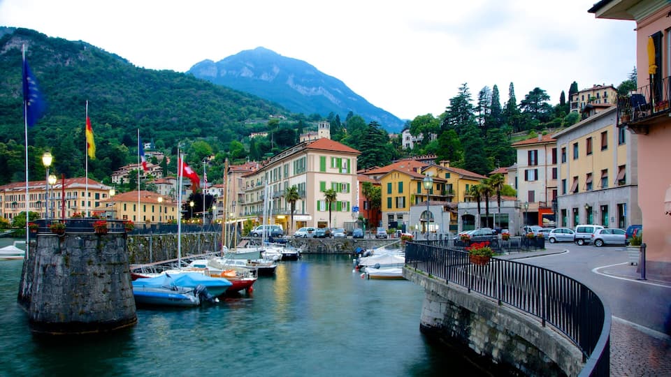 A harbor with boats, a stone bridge, and colorful buildings with a mountain in the background.