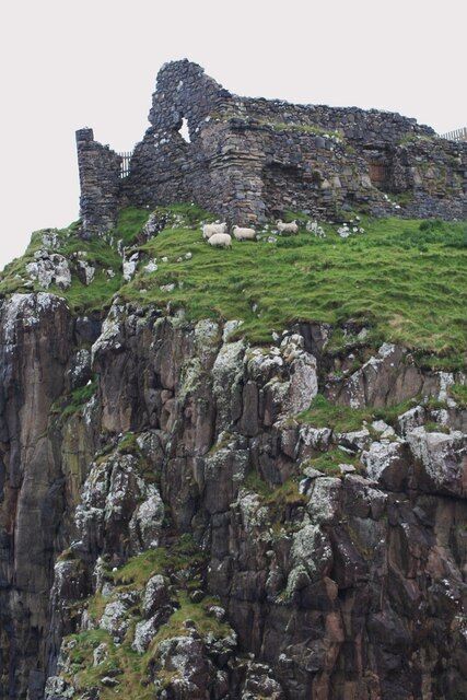 Una estructura de piedra en ruinas sobre un acantilado cubierto de hierba.