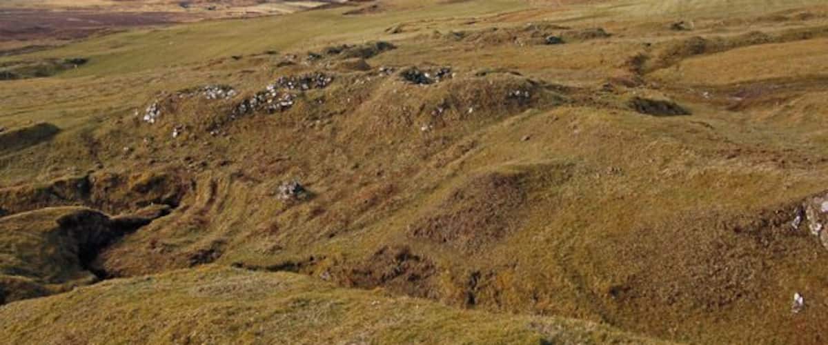 Rolling hills with sparse vegetation and a clear sky.