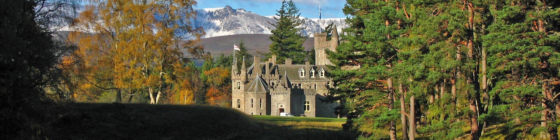 A castle surrounded by autumn trees and a lake.