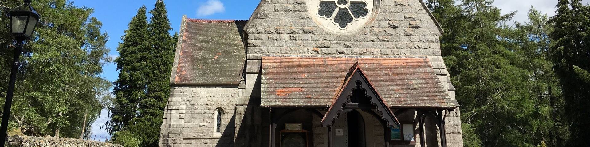A stone church with a large circular window and a cross on top.