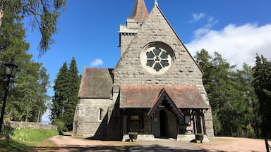 Igreja de pedra com uma grande janela circular e uma cruz no topo.