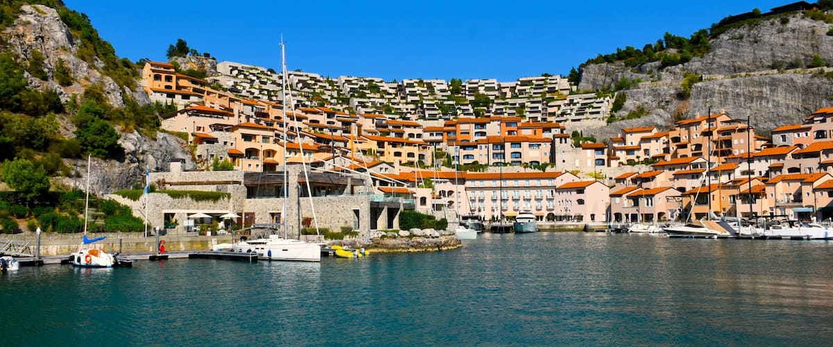 A coastal village with terraced houses, a marina, and boats.