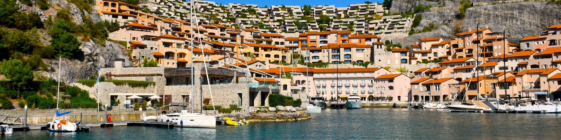 A coastal village with terraced houses, a marina, and boats.