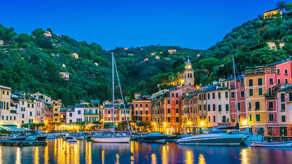A coastal town with colorful buildings, a marina, and a hilltop church.