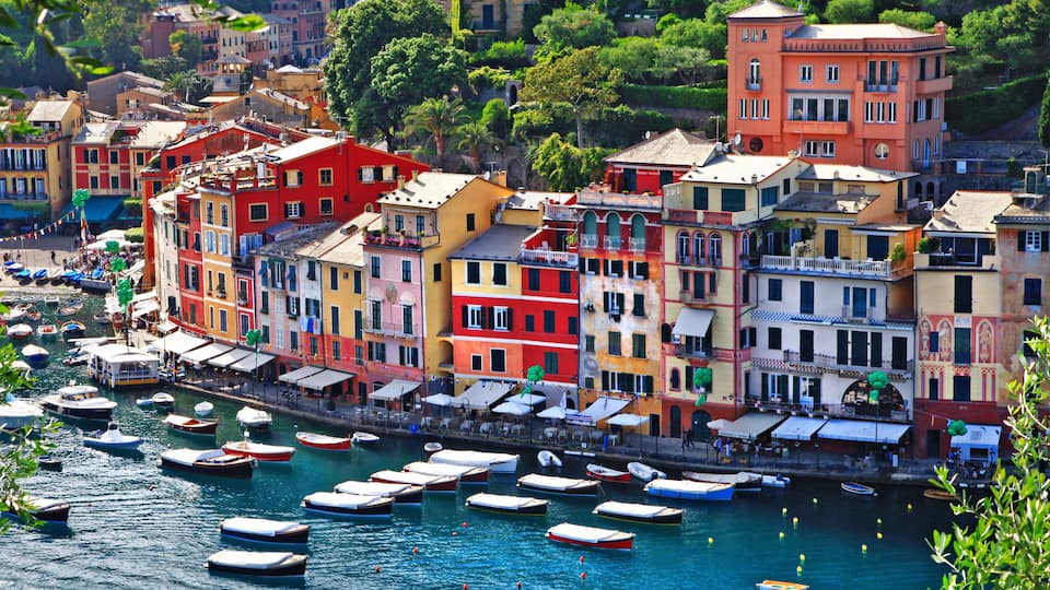 A coastal town with colorful buildings and numerous boats docked along the waterfront.