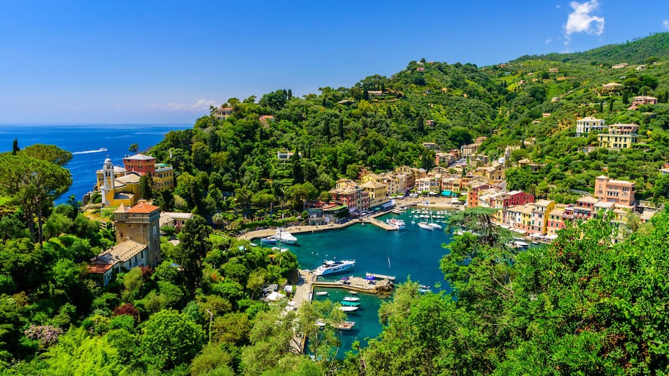A coastal town with a marina, lush greenery, and Mediterranean-style architecture.