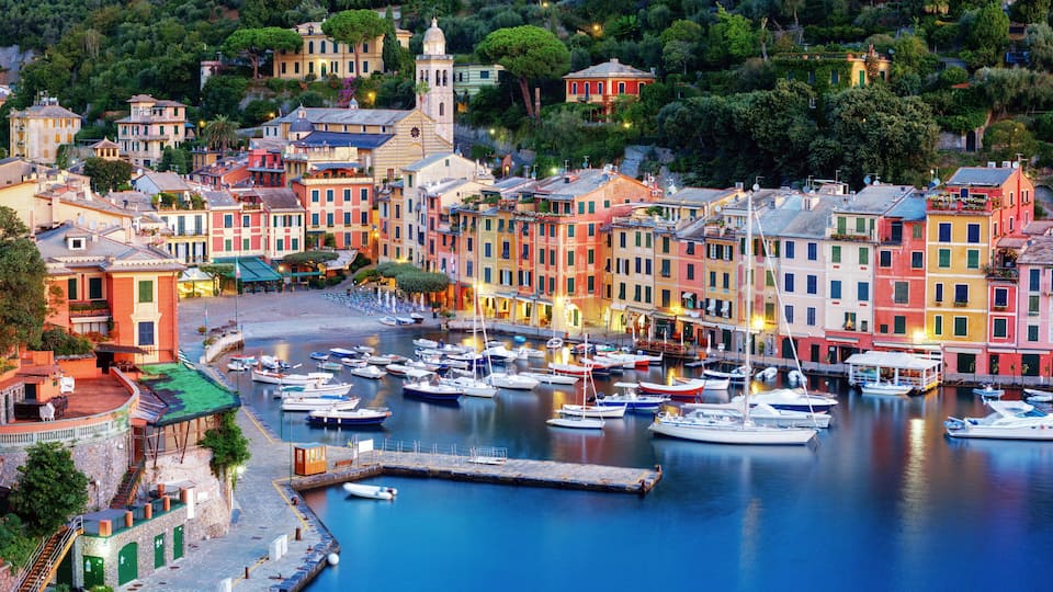 A coastal town with colorful buildings, a marina with boats, and a prominent church tower.