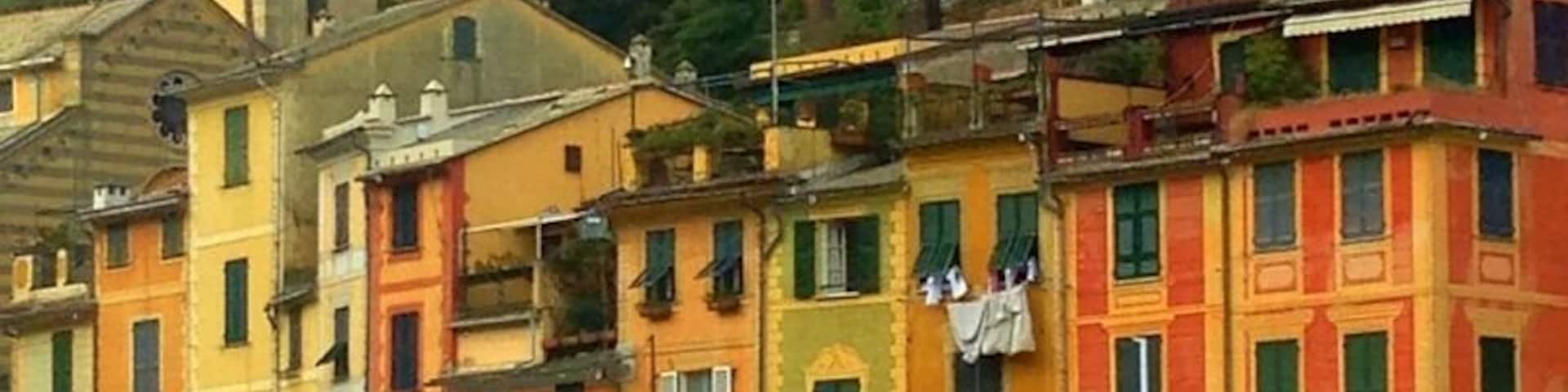 Edifícios coloridos, uma placa com a mensagem 'Portofino Welcome' e uma torre de sino.