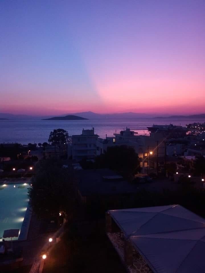 A coastal town at dusk with a view of the sea and a distant island.