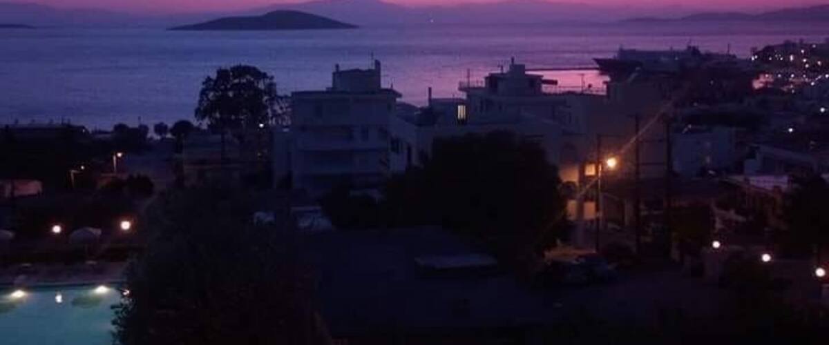 A coastal town at dusk with a view of the sea and a distant island.