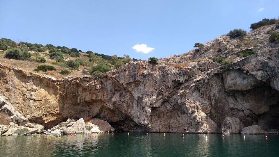 A rocky cliff with a body of water in the foreground.